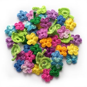 Puede incluir: Una colección de flores de ganchillo de colores en varios tonos de rosa, morado, azul, verde, amarillo y naranja. Las flores son de diferentes tamaños y formas, y algunas tienen hojas adjuntas.