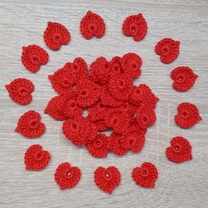 May include: A collection of red crocheted hearts, some are arranged in a circle, while others are piled in the center.