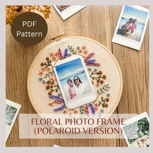 Peut inclure: Un cerceau à broder avec un fond blanc et une broderie florale. Une photo Polaroid de deux personnes sur une plage est affichée au centre du cerceau. Le cerceau est entouré de fleurs de différentes couleurs, dont du rose, du violet, de l'orange et du vert. Le texte "CADRE PHOTO FLORAL (VERSION POLAROID)" est écrit sous le cerceau.