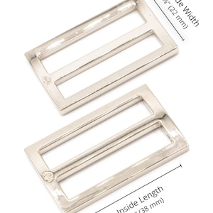 May include: Two silver-colored rectangular metal sliders with three openings. The inside width is 7/8 inches (22 mm), and the inside length is 1 1/2 inches (38 mm). The image includes text indicating the dimensions.