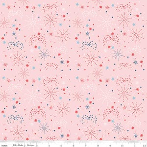 May include: A light pink fabric with a repeating pattern of fireworks, stars, and dots in red, white, and blue. The design includes various sizes and styles of starbursts and firework bursts. The fabric is measured in inches.