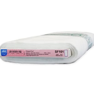 May include: A roll of white Pellon Shape-Flex SF101 fusible interfacing fabric. The label indicates 100% cotton material, machine wash warm and tumble dry medium instructions, and the product is made in the USA. The roll is wrapped in plastic.