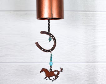 May include: A copper wind chime featuring a cylindrical top, a metal horseshoe suspended by a chain, and a dangling horse silhouette charm accented with small turquoise-colored beads and a tiny heart-shaped pendant.