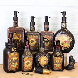 K&ouml;nnte beinhalten: Eine Sammlung dunkelbrauner Seifenspender aus Glas mit schwarzen Pumpk&ouml;pfen, versehen mit Etiketten im Vintage-Stil, die Flederm&auml;use und Spinnen zeigen, Text wie Doctor Kellogg und Vampires enthalten und kleine metallische Zahnr&auml;der am Hals.