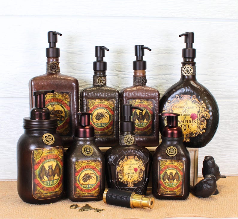 K&ouml;nnte beinhalten: Eine Sammlung dunkelbrauner Seifenspender aus Glas mit schwarzen Pumpk&ouml;pfen, versehen mit Etiketten im Vintage-Stil, die Flederm&auml;use und Spinnen zeigen, Text wie Doctor Kellogg und Vampires enthalten und kleine metallische Zahnr&auml;der am Hals.