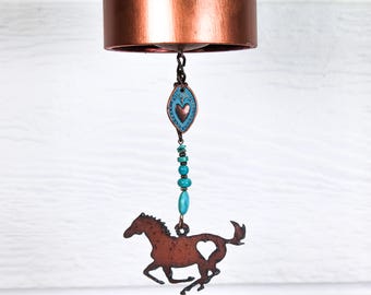 May include: A copper wind chime component featuring a cylindrical top, a turquoise-colored heart charm, a strand of small turquoise beads, and a flat, dark copper-toned horse silhouette pendant with a heart-shaped cutout in its center.