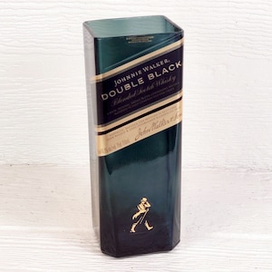 May include: A green glass bottle with a gold label that reads "JOHNNIE WALKER. DOUBLE BLACK Blended Scotch Whisky" and a walking man logo.