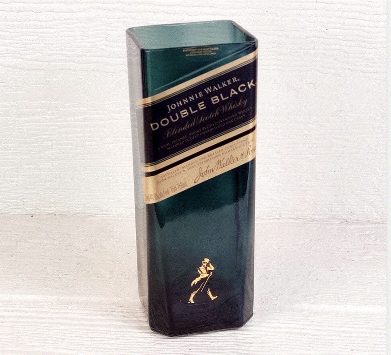 May include: A green glass bottle with a gold label that reads "JOHNNIE WALKER. DOUBLE BLACK Blended Scotch Whisky" and a walking man logo.