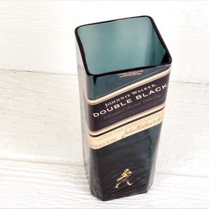 May include: A dark green glass vase with a square shape. The vase is made from a recycled Johnnie Walker Double Black Blended Scotch Whisky bottle. The label on the bottle reads "Johnnie Walker Double Black Blended Scotch Whisky".