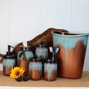 May include: A bathroom accessory set featuring a soap dispenser, tissue holder, two lidded jars, a toothbrush holder, and a wastebasket. Each item has a copper-colored base with a distressed turquoise drip pattern and black metal lids.