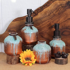 May include: A collection of copper-colored glass bottles with turquoise accents. Two bottles have black pump dispensers. The bottles are displayed on wooden stands, with a yellow sunflower and two small bird figurines.