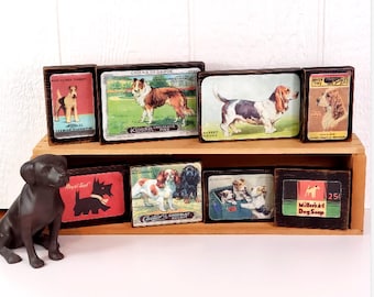 May include: A set of eight vintage-style wooden blocks with images of dogs and dog-related products. The blocks feature illustrations of various dog breeds, including a Collie, Basset Hound, and a terrier. The blocks also feature advertisements for dog food, dog biscuits, and dog soap.