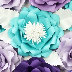 May include: A collection of paper flowers in shades of purple, lavender, and turquoise. The flowers are arranged in a close-up view, showcasing their intricate details and delicate textures.
