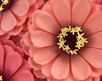 May include: Close-up of a large, pink paper flower with a burgundy center and yellow accents. The flower has many layers of petals and is made of paper.