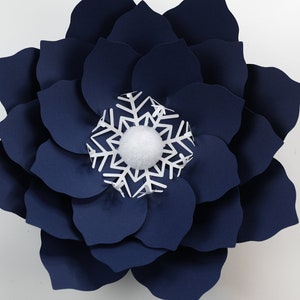 Pu&ograve; includere: Un grande fiore di carta blu navy con un fiocco di neve bianco e un pon pon bianco al centro.