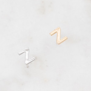 May include: Two small earrings in the shape of the letter Z. One earring is silver and the other is gold.