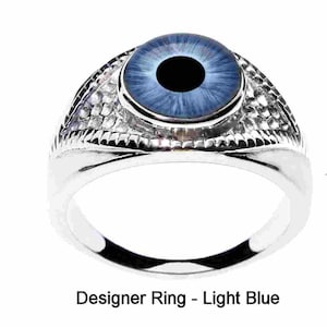 May include: A silver ring with a light blue eye design. The ring has a textured band.