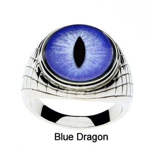 May include: A silver ring with a blue eye design. The eye is surrounded by a silver ring and the band of the ring has a textured pattern.