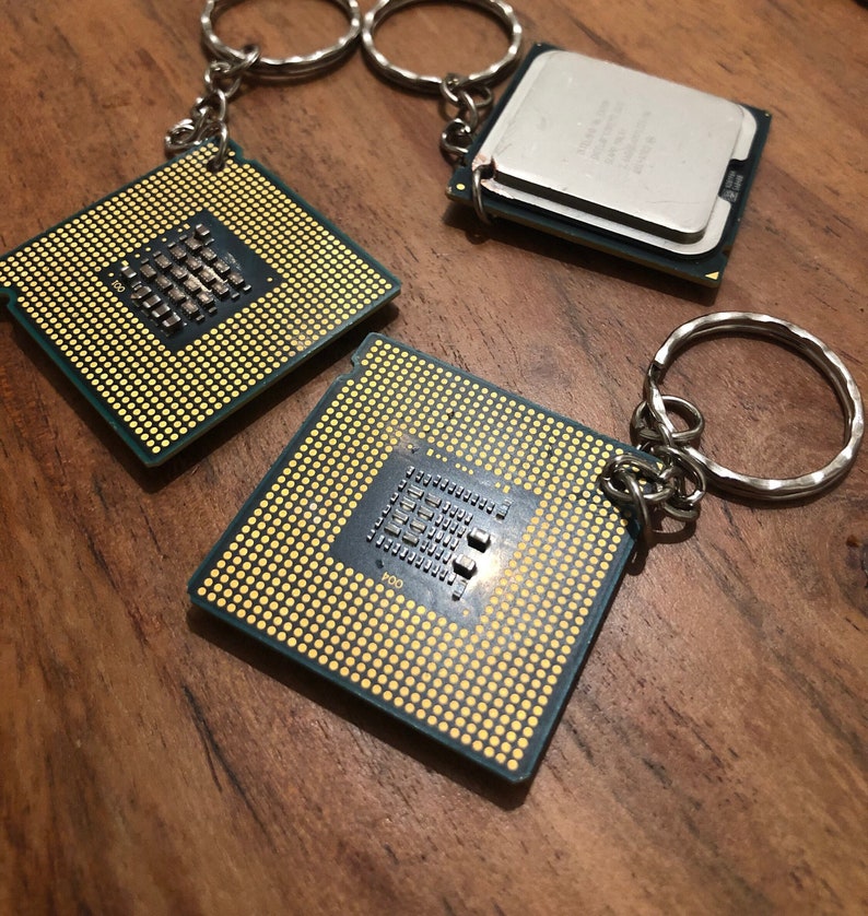 May include: Three silver keychains with a gold-colored CPU chip attached to each. The chips have a grid pattern and small black squares.