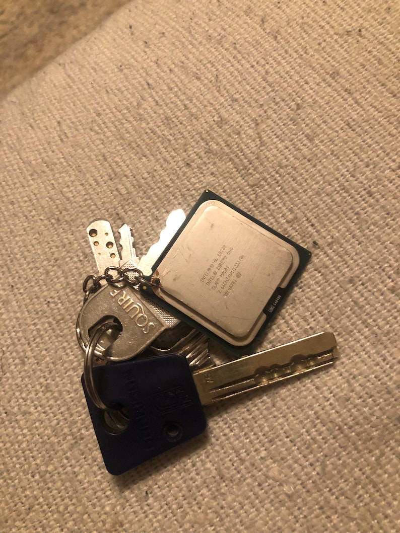 May include: A silver keychain with a blue and silver key fob, a silver key with a silver key fob that says "Squire", and a silver computer chip with the text "Intel Pentium 4 2.80 GHz 512KB L2 Cache 800 MHz FSB" on it.