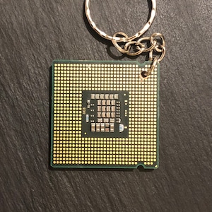 May include: A green circuit board keychain with a gold-colored chip and the number "003" printed on it.