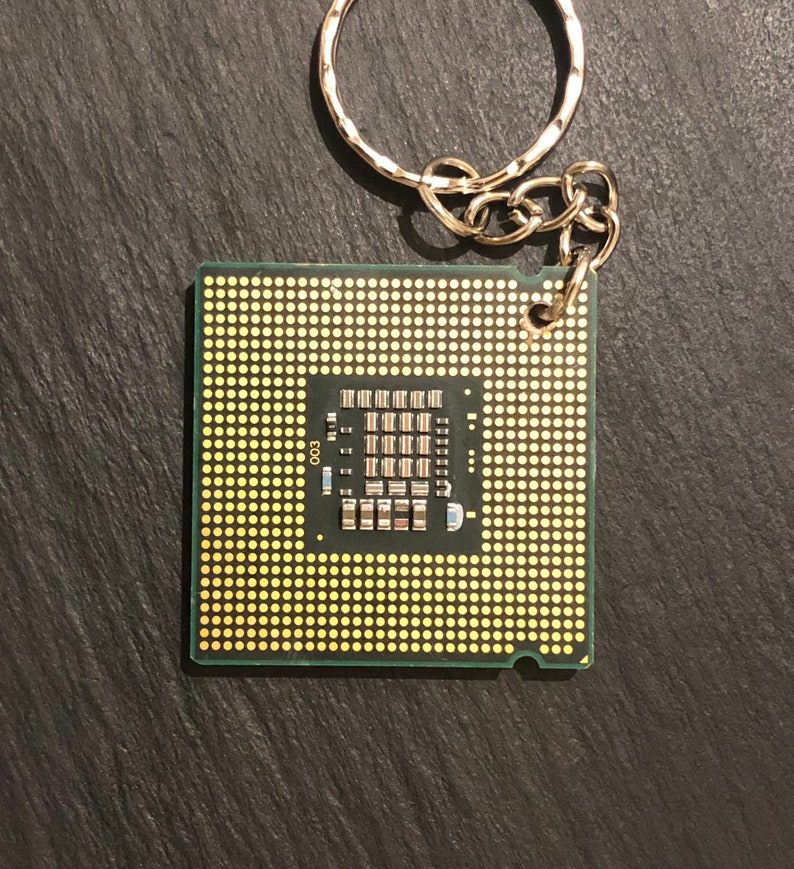 May include: A green circuit board keychain with a gold-colored chip and the number "003" printed on it.