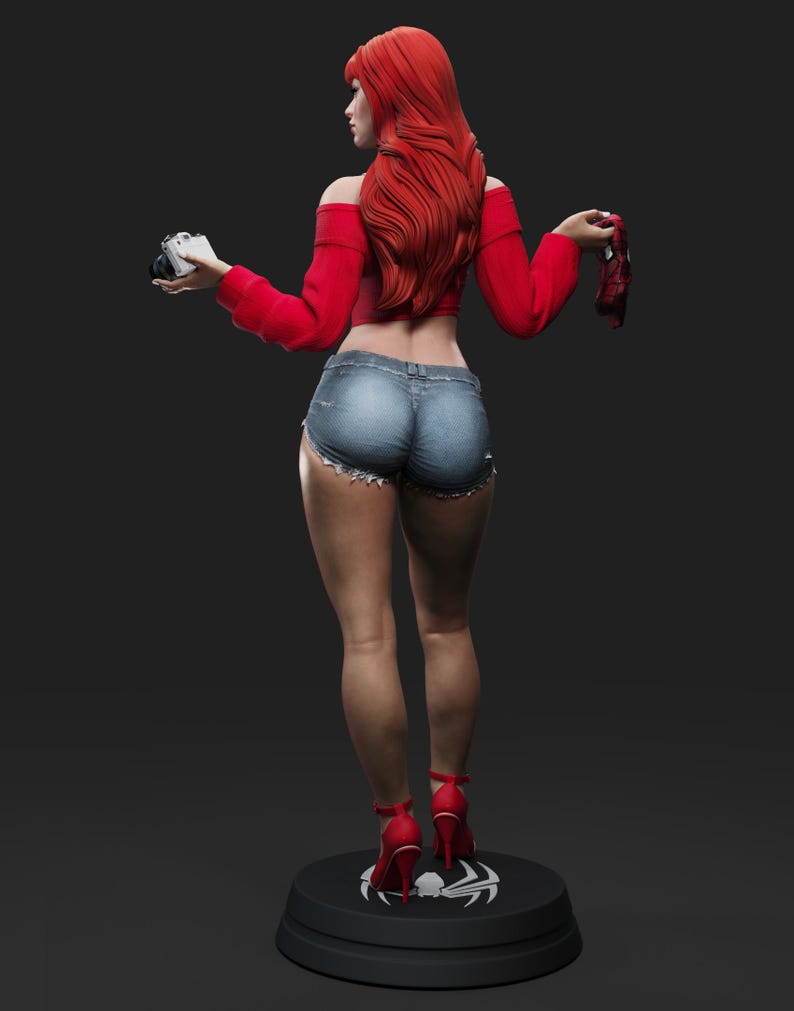 May include: A figurine of a woman with long red hair, wearing a red off-the-shoulder top, denim shorts, and red high heels. She holds a camera in one hand and a red mask in the other. The figurine stands on a black base with a white spider symbol.