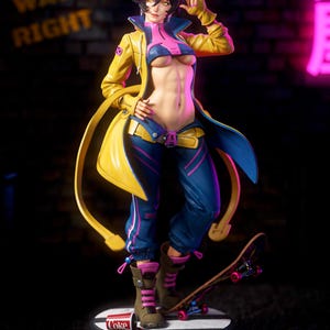 May include: A collectible figurine of a character with short black hair and yellow eyes, wearing a yellow jacket, pink top, and blue pants. The figure stands on a circular base with a skateboard and a spilled Coke cup, featuring an X-Men logo.