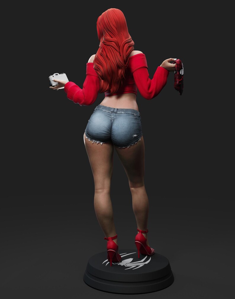 May include: A figurine of a woman with long red hair, wearing a red off-the-shoulder top, denim shorts, and red high heels. She holds a camera and a mask. The figurine stands on a black base with a white spider logo.