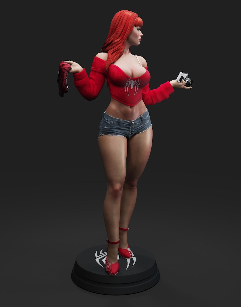 May include: A statue of a woman with red hair, wearing a red top with a spider emblem, denim shorts, and red shoes. She holds a camera and a pair of red gloves. The statue stands on a black base with a white spider symbol.