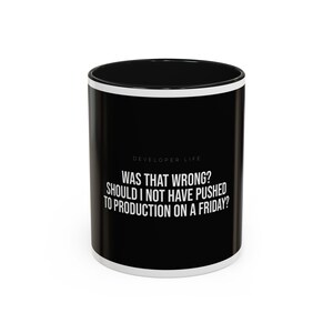 May include: Black ceramic mug with white trim and the text "DEVELOPER LIFE WAS THAT WRONG? SHOULD I NOT HAVE PUSHED TO PRODUCTION ON A FRIDAY?" in white. The mug is cylindrical and suitable for hot beverages.