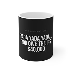 Può includere: Tazza in ceramica nera con interno bianco. La tazza presenta il testo "ACCOUNTANT LIFE" sopra la frase "YADA YADA YADA... YOU OWE THE IRS $40.000" in bianco. La tazza è cilindrica e ha un interno bianco.