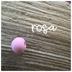 May include: A single pink wooden bead on a wood background. The word "rosa" is written in white above the bead.