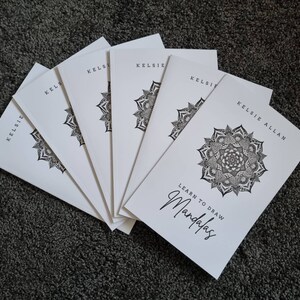 May include: A stack of six white paperbacks with black text and illustrations. The front cover features a black and white mandala design and the text "Learn to Draw Mandalas". The author's name, "Kelsie Allan", is printed on the cover.
