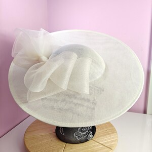 May include: A white wide-brimmed hat with a large white bow made of netting.