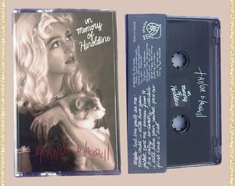 May include: A vintage cassette tape featuring a monochrome image of a woman and a cat. The text on the cassette reads "In Memory of Haroldine" and "Taylor & Lacknell."