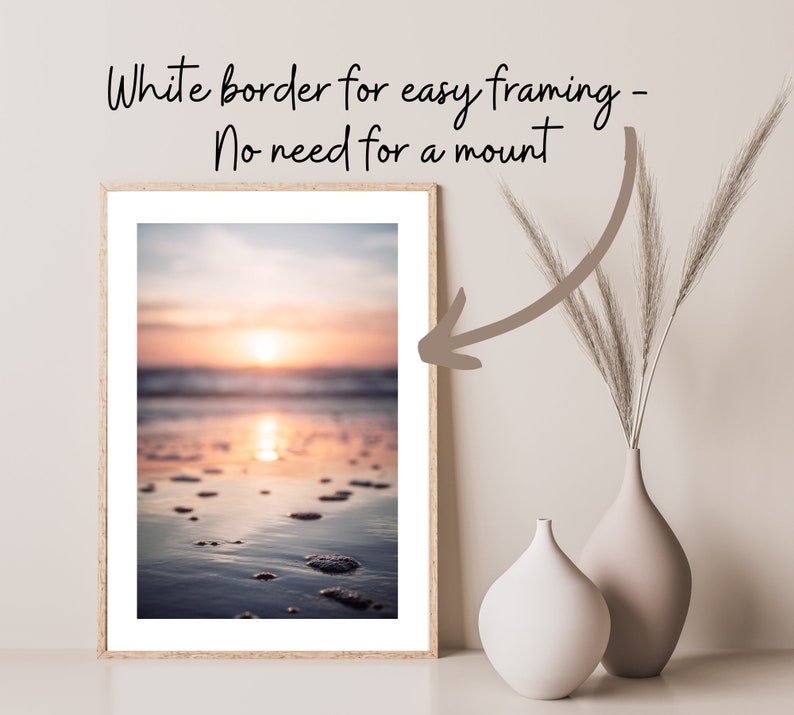 May include: A framed vertical print of a sunset over the ocean with a white border. The text above the print reads: White border for easy framing - No need for a mount. A curved arrow points from the text to the white border of the print.
