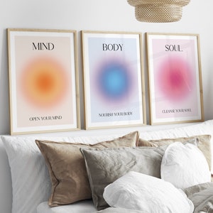 May include: Three framed prints with gradient backgrounds and text. The first print is orange and says "MIND OPEN YOUR MIND". The second print is blue and says "BODY NOURISH YOUR BODY". The third print is pink and says "SOUL CLEANSE YOUR SOUL".