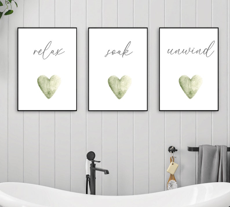 May include: Three framed prints with white backgrounds and black frames. Each print features a green watercolor heart and a handwritten word: "relax", "soak", and "unwind".