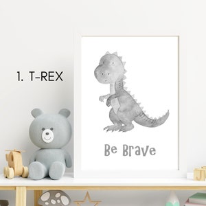 Puede incluir: Una ilustraci&oacute;n de acuarela en blanco y negro de un dinosaurio T-Rex con el texto "Be Brave" debajo. La ilustraci&oacute;n est&aacute; enmarcada en un marco blanco y est&aacute; sentada en un estante blanco.