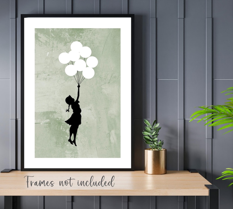 May include: A black silhouette of a person holding white balloons against a green textured background. The image is framed in black.
