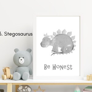 Puede incluir: Una ilustraci&oacute;n de acuarela en blanco y negro de un estegosaurio con el texto "Be Honest" impreso debajo. La ilustraci&oacute;n est&aacute; enmarcada y se muestra en un estante con un oso de peluche gris y otros art&iacute;culos decorativos.