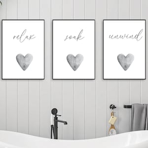 May include: Three framed prints with black frames and white backgrounds. Each print features a gray watercolor heart and a word in black script: "relax", "soak", and "unwind".