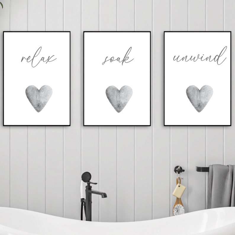 May include: Three framed prints with black frames and white backgrounds. Each print features a gray watercolor heart and a word in black script: "relax", "soak", and "unwind".