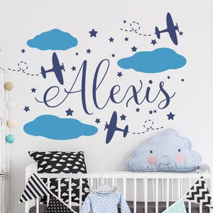 May include: Blue and white airplane themed nursery wall decal with the name Alexis. The decal features clouds, stars, and airplanes.
