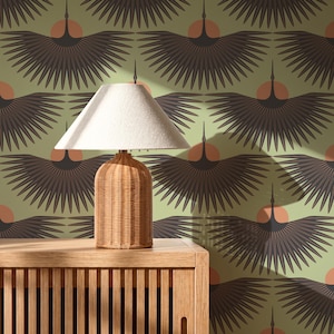 May include: A table lamp with a woven rattan base and a white fabric shade sits atop a light wood slatted cabinet. The background features wallpaper with a repeating pattern of dark brown stylised birds with wings spread over orange circles.