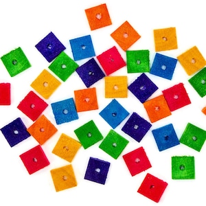 May include: A collection of colorful wooden squares with a hole in the center. The squares are scattered on a white background. The colors include red, orange, yellow, green, blue, purple, and pink.