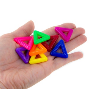 May include: A hand holding a collection of colorful plastic triangle shapes. The triangles are in various colors, including red, orange, yellow, green, blue, purple, and pink.