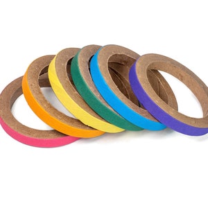 May include: A collection of colorful washi tape rolls in a rainbow of hues. The rolls are arranged in a row, showcasing the vibrant pink, orange, yellow, green, blue, and purple colors. The tape has a textured, natural brown core.