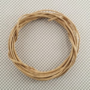 May include: A close-up of a brown paper twine wound into a circle on a gray and white checkered surface.